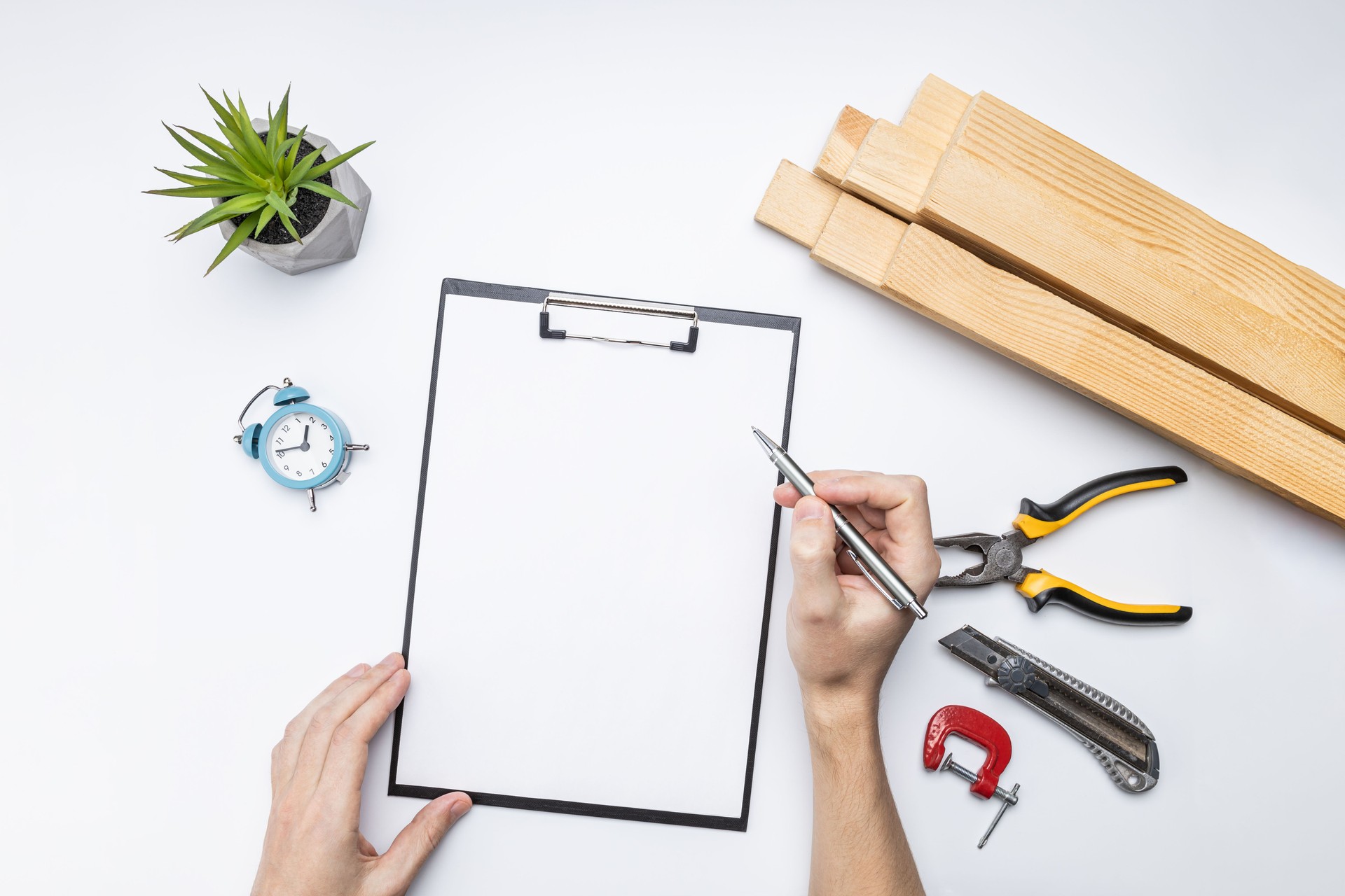 carpenter planning work concept. above view. blank clipboard, wooden planks and tools at white desk. handyman checklist conceptual